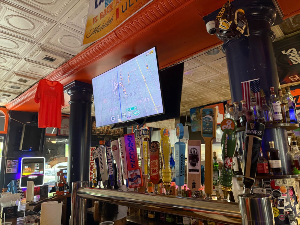 The tap lineup at the bar, local handles and national brands under a football game on screen