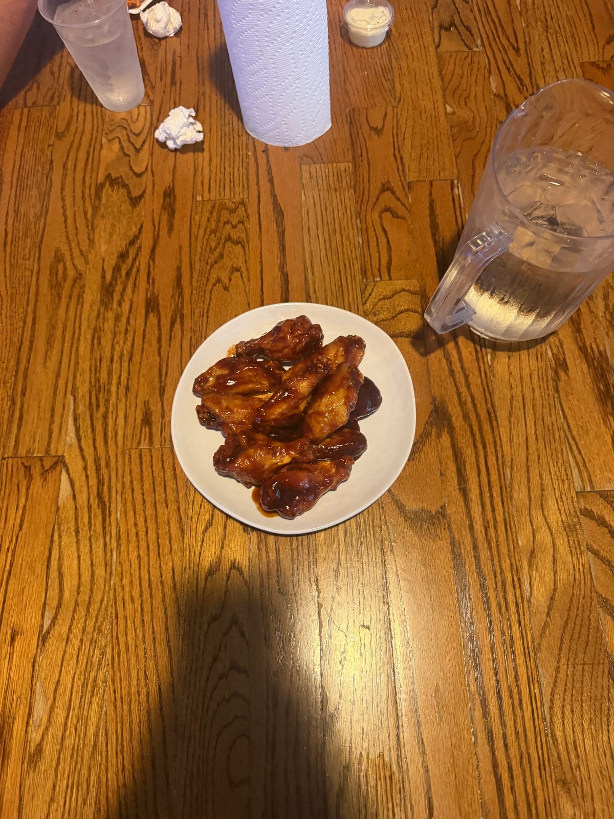 Plate of barbecue wings glazed in sauce on a wood table