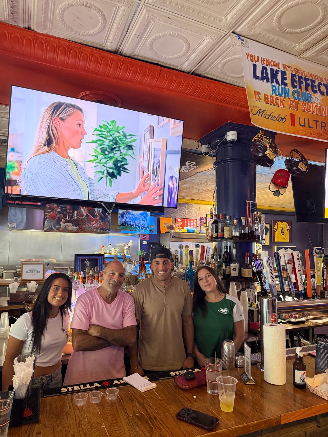 Four staff members behind the bar under the taps and screens
